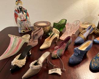 Lots of glass shoes on display, pink and green glass slipper is Fenton.