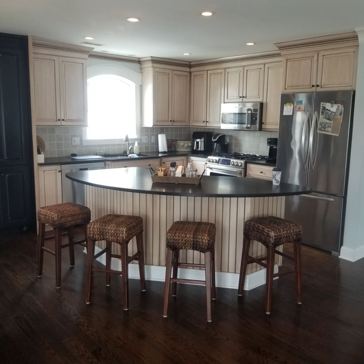 Handsome kitchen cabinetry by KountryKraft; bar stools