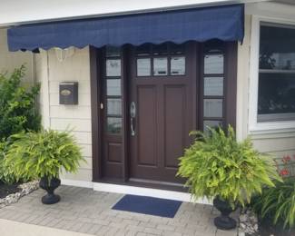 Spectacular entry door with two side lights; fixed awning; potted ferns