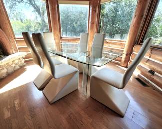 Modern Glass Top Table with 6 Faux Leather Chairs. One chair and a light soil mark and the other has some peeling (see photos)