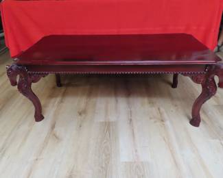 Cherry colored coffee table with corner horse head legs. 