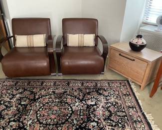 Art Deco leather armchairs with lumbar pillows, wool area rug, storage side table and decor
