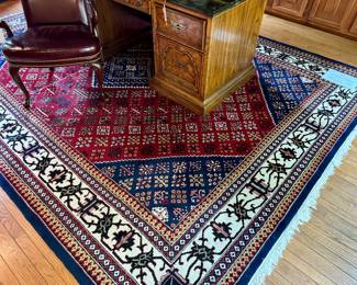 $850; wool, knotted rug with navy and wine primary colors and fringe on two short sides; approx 9.5’x12’