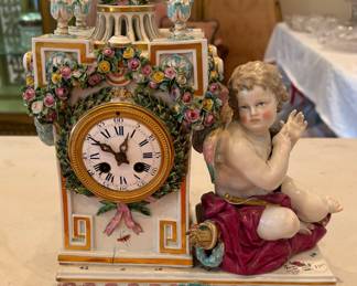 Meissen porcelain clock with angel seated, pair of doves on top, decorated with lavish garlands of porcelain roses, has pendulum and key.