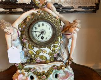Sitzendorf porcelain clock with lady on each side holding garland of porcelain roses, angel seated on top of clock holding garland of roses. 