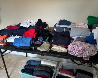 Table filled with women's clothes! Sweaters, Blues etc...