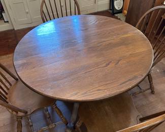 A beautiful solid oak dining table with four Windsor Style chairs! The table comes with a leaf. Without the leaf the table is perfectly round. GREAT condition!
