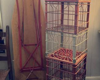 Old ironing board with red base, metal milk crates, wooden tool box