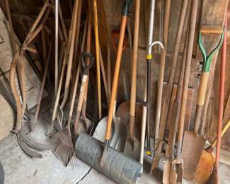 A lot of outdoor yard tools - rakes, shovels, brooms, post hole diggers, clippers 