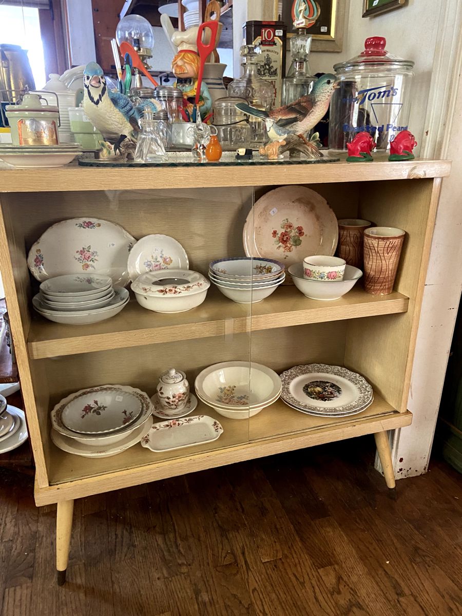 Blonde MCM glass front cabinet with antique china pieces.