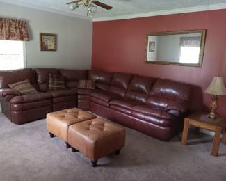 Sectional sofa, ottoman, end table with lamp, framed mirror, wall decor.