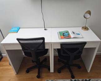 Two small white desks and two black mesh desk chairs 
