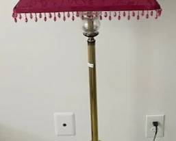 Brass floor lamp with red fringed shade.