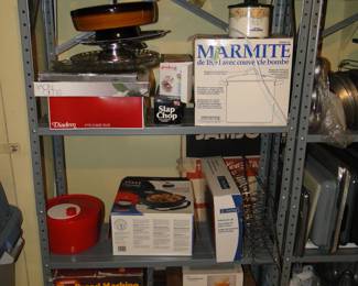 More metal shelving, with a bread machine, cookie tins, serving platters, and a salad spinner