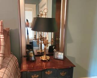 Bedside table with floor mirror behind 