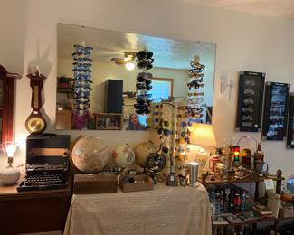 A small globe collection, several pairs of sunglasses, far right is another Harley Davidson display, and the shelves are filled with great decorative items and a nice Avon collection of automobile cologne decanters