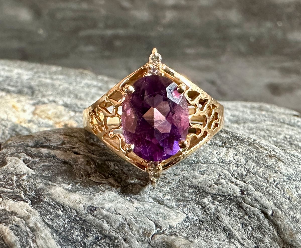 A beautiful 14K gold ring with a large oval-cut Amethyst center stone and four small genuine diamonds above and below the center stone. Total weight of 4.1 grams. Ring size is 6.5.