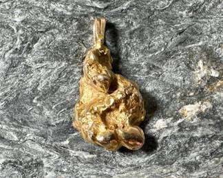 A 14k gold nugget pendant. Approx. weight is 6.50 grams. Measures 1'' tall and around 1/2'' wide.