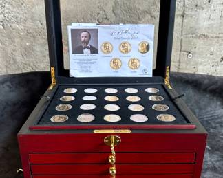 A decorative wooden box containing 95 presidential commemorative dollars in uncirculated/proof condition in plastic coin protectors, from George Washington to Rutherford B. Hayes. In addition, 5 more circulated dollar coins including Sacagawea and assorted presidents, for a total of 100 coins. The box has multiple drawers with coin holding trays to display the presidential $1 coins.