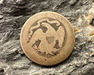 An 1877 CC Liberty Seated Quarter. Minted at the Carson City Mint. Estimated condition About Good.