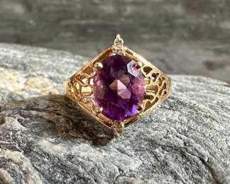 A beautiful 14K gold ring with a large oval-cut Amethyst center stone and four small genuine diamonds above and below the center stone. Total weight of 4.1 grams. Ring size is 6.5.