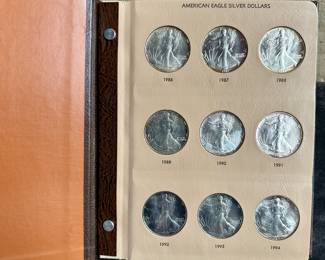 A Dansco American Eagle Silver Dollar coin folder with 14 1 oz. troy American Silver Eagles, 1986-1999.