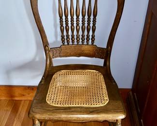 Antique pressed back wooden chair with spindle back and caned seat