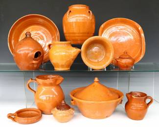 Twelve pieces of 20th century Jugtown Pottery.  Various forms with mottled Orange glaze, includes a pie dish, covered tureen, serving plate with folded side handles, Chinese style vase, pitcher, birdhouse, teapot, creamer, bowl, two covered jars and a handled ramekin.  Impressed "Jugtown Ware" marks.  Most with some damage including flakes, chips, hairlines and/or repairs, some crazing and surface wear, teapot lacks lid, sold AS-IS.  Up to 9 3/4" diameter and 9" high.  ESTIMATE $50-100