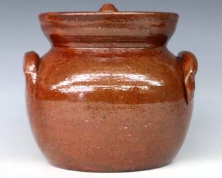 An early 20th century Jugtown Pottery covered jar.  Bulbous form with recessed lid, applied strap handles and mottled Red/Brown Tobacco Spit glaze.  Impressed "Jugtown Ware" mark.  Minor wear, some scratches at shoulder.  7 1/4" high.  ESTIMATE $50-100