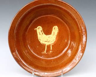 A 20th century Jugtown Pottery bowl.  Low bowl with Yellow Chicken decoration and mottled Red/Brown glaze.  Impressed "Jugtown Ware" mark.  Minor wear and crazing.  10" diameter x 2 3/4" high.  ESTIMATE $50-100