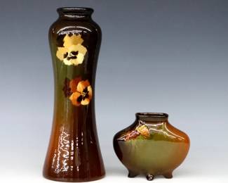 Two turn of the century Ohio Valley Art Pottery vases with Brown Standard glaze.  Includes an unmarked baluster lamp base with multi-color Pansy decoration, and a small J.B. Owens pillow vase with multi-color Clover decoration.  Lamp with incised "A" and "X" factory mark, vase with impressed "Utopian / J.B. Owens" and "846" marks.  Slight wear and some crazing, lamp base with surface wear at rim.  4" and 10 1/2" high.  ESTIMATE $50-100