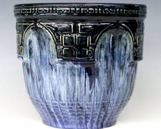 An early 20th century Brush McCoy Art Pottery jardiniere.  Ribbed body with molded Arts & Crafts floral decoration and gradient Blue Majolica glaze.  Impressed "242" at underside.  Minor wear and crazing.  8 3/4" diameter x 8' high.  ESTIMATE $50-100
