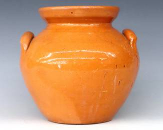 A 20th century Jugtown Pottery jar.  Bulbous form with applied strap handles and mottled Orange glaze.  Impressed "Jugtown Ware" mark.  Some crazing and flakes, hairline to glaze at lower body from production, lacks cover.  8" high.  ESTIMATE $25-50