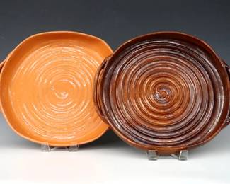 Two 20th century Jugtown Pottery casserole dishes.  Circular forms with two handles and swirled decoration with Orange and Oxblood glaze.  Impressed "Jugtown Ware" marks.  Some crazing and flakes particularly to Orange dish.  Up to 15" long.  ESTIMATE $50-100