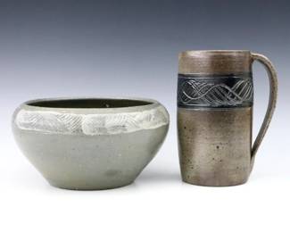 A 20th century Jugtown Pottery bowl and mug.  Tapered and cylindrical forms with incised decoration and Grey and Brown glaze.  Impressed "Jugtown Ware" marks.  Minor wear.  Bowl is 8 1/2" diameter x 4 1/2" high, mug is 7 1/8" high.  ESTIMATE $50-100