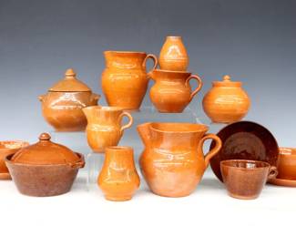 Fifteen pieces of 20th century Jugtown Pottery.  Various forms with mottled Orange, Red/Brown Tobacco Spit, and Orange/Green Accidental glazes.  Includes three pitchers, two covered jars, a covered pot, two vases and three teacups with saucers.  Impressed "Jugtown Ware" marks.  Some with crazing and flakes, several pieces with painted undersides or touch-ups.  Up to 6" diameter and 5" high.  ESTIMATE $50-75