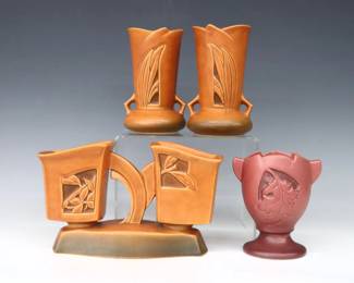 Four pieces of mid 20th century Roseville Art Pottery with "Silhouette" foliate decoration.  Includes a pair of tapered vases and a double planter with Orange/Brown matte glaze, and a urn form pedestal vase with Mauve/Red matte glaze.  Molded "Roseville / U.S.A" marks and model numbers, single vase also with "X" factory mark.  Minor surface wear and discoloration, single vase with production glaze flaw at leaf.  Up to 9 1/2" long and 6 1/4" high.  ESTIMATE $50-100