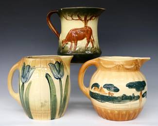 Three turn of the century Roseville Pottery pitchers.  Various forms with hand-painted Cow, Tulip and landscape decoration.  Unmarked.  Crazing, some flakes and chips, tulip pitcher with glued break at rim.  Up to 7 1/2" high.  ESTIMATE $50-75