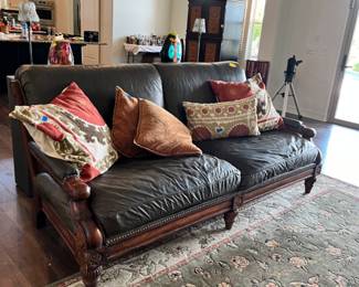 Tuscan style leather sofa with nailhead in a dark cherry wood finish.