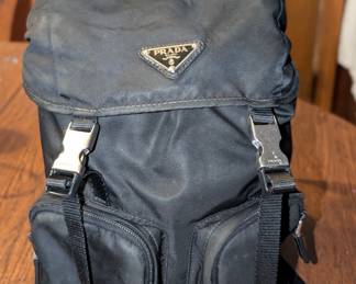 Vintage Prada black nylon backpack. This does have all the right markings in all the right places, but has not been authenticated. One of the photos does show one prong of the plastic clip as broken. This is a generic piece and can be replaced. Only the metal pieces and inside nylon lining have the Prada markings, not the black plastic clips.