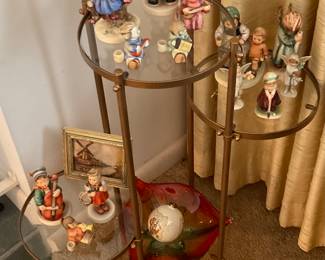 GLASS AND BRASS THREE-TIERED TABLE WITH HUMMELS