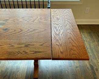 P4 - $400. Solid Wood Trestle style dining table. Has stain on the top but it's in the finish not the wood - wood is *not* warped.  Measures 48" wide x 34" deep  x 30.5" tall. 2 leaves slide into the ends and add 24" total (12" each leaf). Quality Construction! Beautiful piece - easy refinish project. 