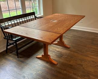 P4 - $400. Solid Wood Trestle style dining table. Has stain on the top but it's in the finish not the wood - wood is *not* warped.  Measures 48" wide x 34" deep  x 30.5" tall. 2 leaves slide into the ends and add 24" total (12" each leaf). Quality Construction! Beautiful piece - easy refinish project. 