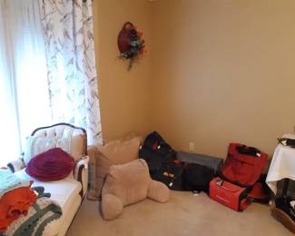 Primary bedroom, chaise lounge, pillows and luggage.  