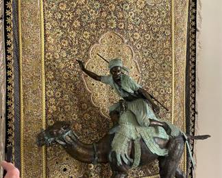 Pierre Jules Mene (French, 1810-1879)Arab Hunter Riding a Camel Bronze alloy 52" x 46" x 17" on a large stand 15"  x 48"  x 21 1/2" on castors  large sculpture reminiscent of Lawrence of Arabia, inspired by an original by Mene, cast in the latter quarter of the 20th century. Unmarked Condition Scattered small deposits of white residue.
