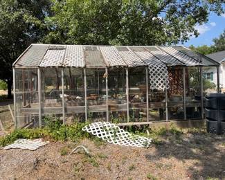 This is a vintage all glass greenhouse! We assume the wood panels were added to either protect the glass or to limit the sunlight coming in. The glass roof is still there.