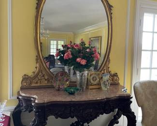 English Rococo mahogany console, heavily carved with pink marble top. Beautiful gold leaf oval mirror. The console is an original to the house