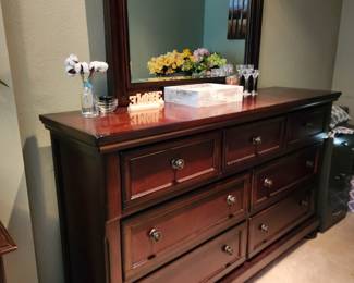 Rich-colored wood bedroom suite includes a Queen bed with headboard, footboard, mattress & box spring, 2 nightstands, and a triple dresser with mirror