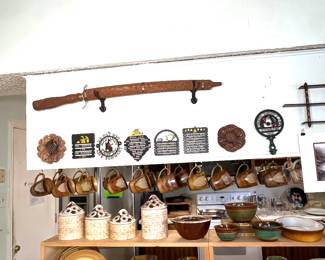 This picture is FULL of goodies. The top of the picture shows the antique sword in a hand carved wooden case.  Below it is a small collection of metal and wooden trivets. The daisy 3-piece cannister set and matching cookie jar is surrounded by a wonderful set of dishes by Santos