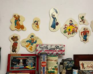 Disney cutouts are on the wall. Below the cutouts are vintage games and toys.  The erector set is absolutely  amazing.